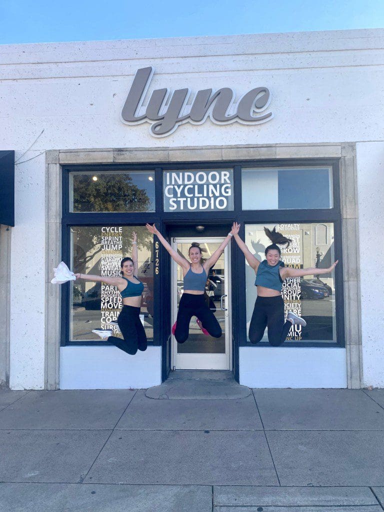Three women jumping outside Lync Cycling Studio