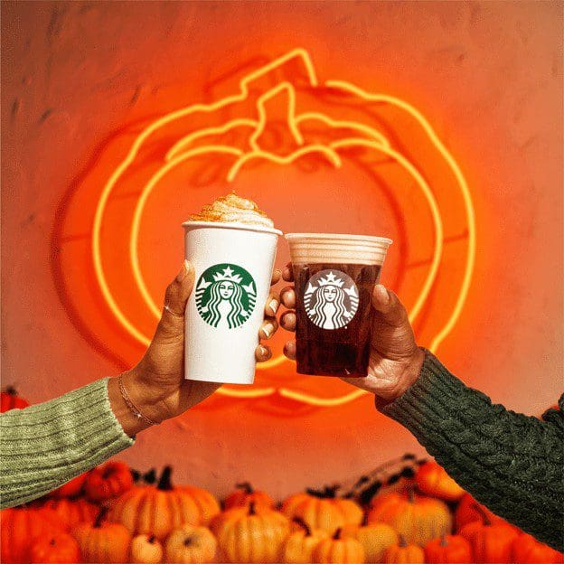 Two hands clinking Pumpkin Spice drinks from Starbucks. 