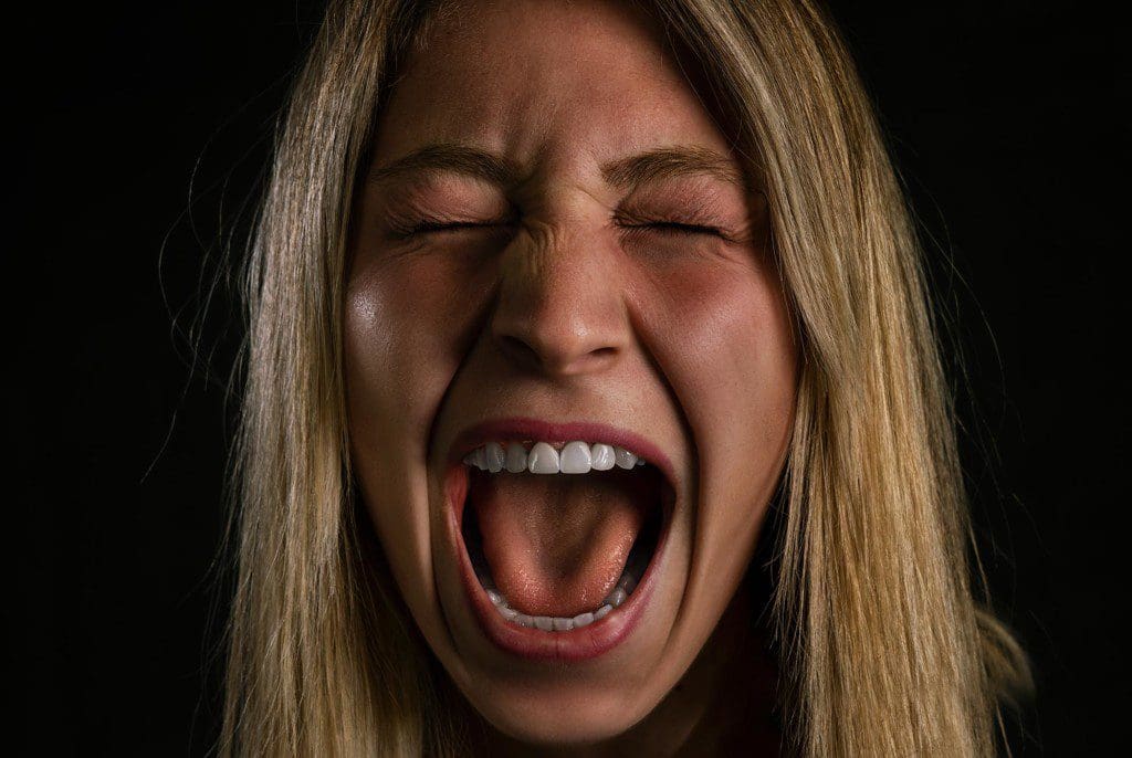 A close up image of a women's face screaming