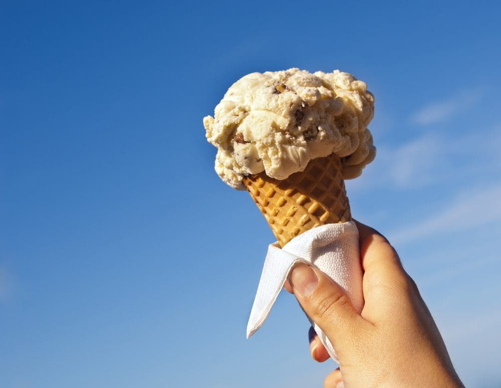 Image of a hand holding an ice cream cone against a blue sky